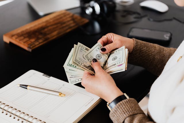 Person counting money infront of a pen and paper